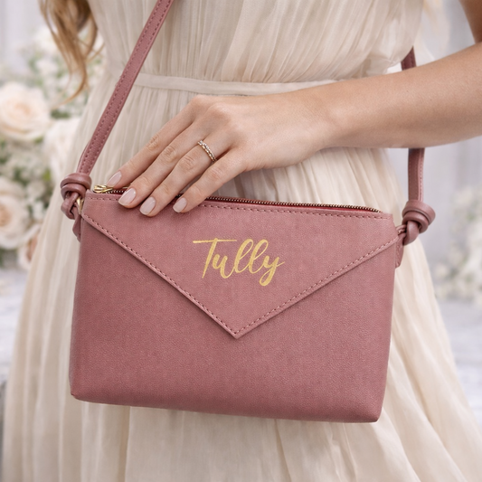 Pink handbag with 'Tully' branding held by a person in a white dress, floral background