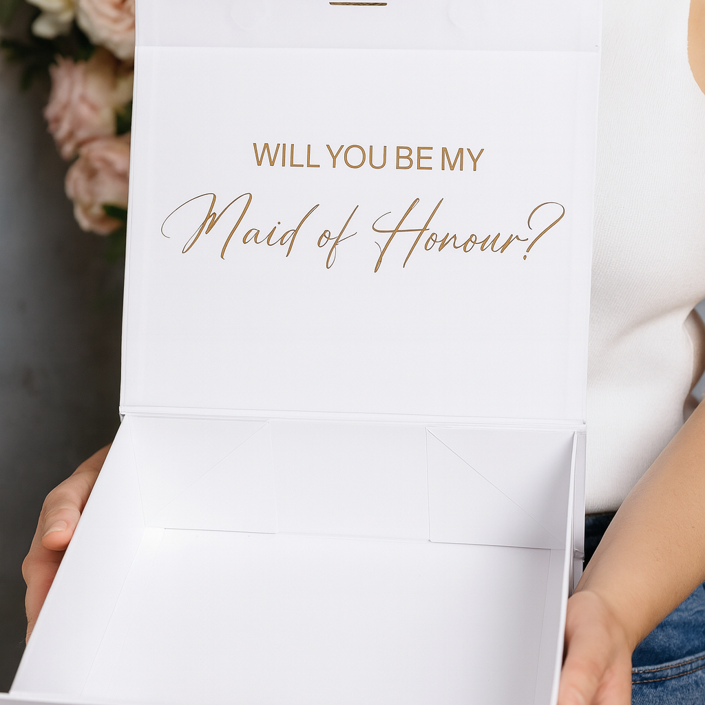 White box with 'Will You Be My Maid of Honour?' text held by a person.