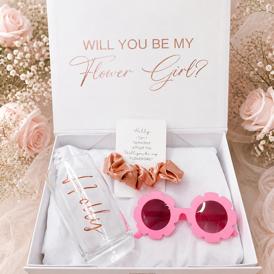 Gift set with pink sunglasses, hair scrunchies, and card in a box with 'Will You Be My Flower Girl?' text.