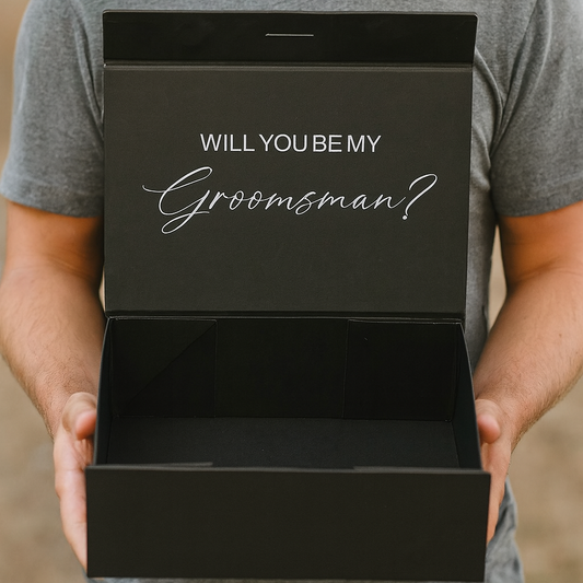 Man holding a black box with 'Will You Be My Groomsman?' text.