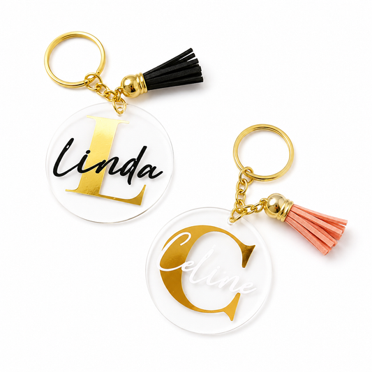 Two keychains with gold lettering and tassels on a white background