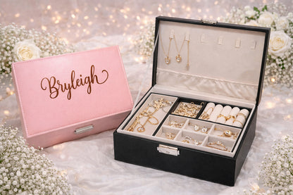 Jewelry box with 'Bryleigh' on a pink cover, filled with jewelry on a decorative background.