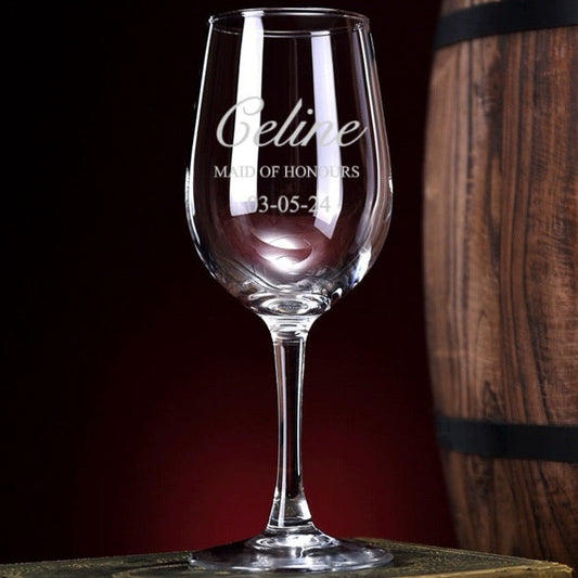 A clear glass wine glass with engraved text on the stem, displayed against a wooden background.