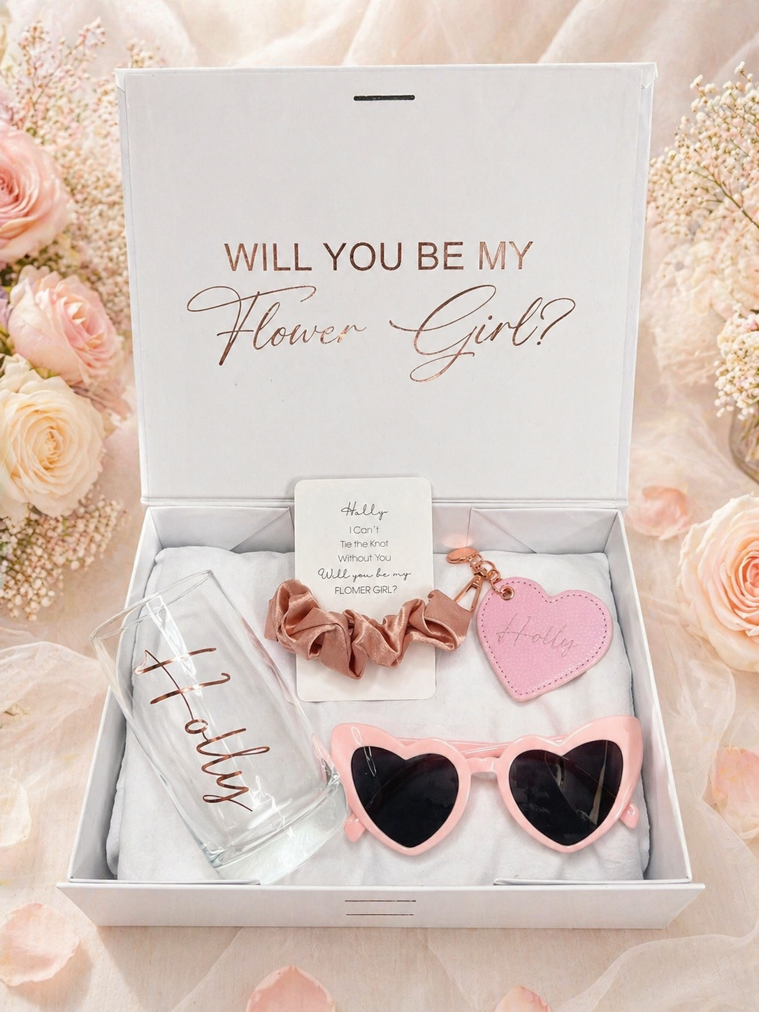 Gift set with sunglasses, scrunchie, and heart-shaped item in a box with 'Will You Be My Flower Girl?' text.