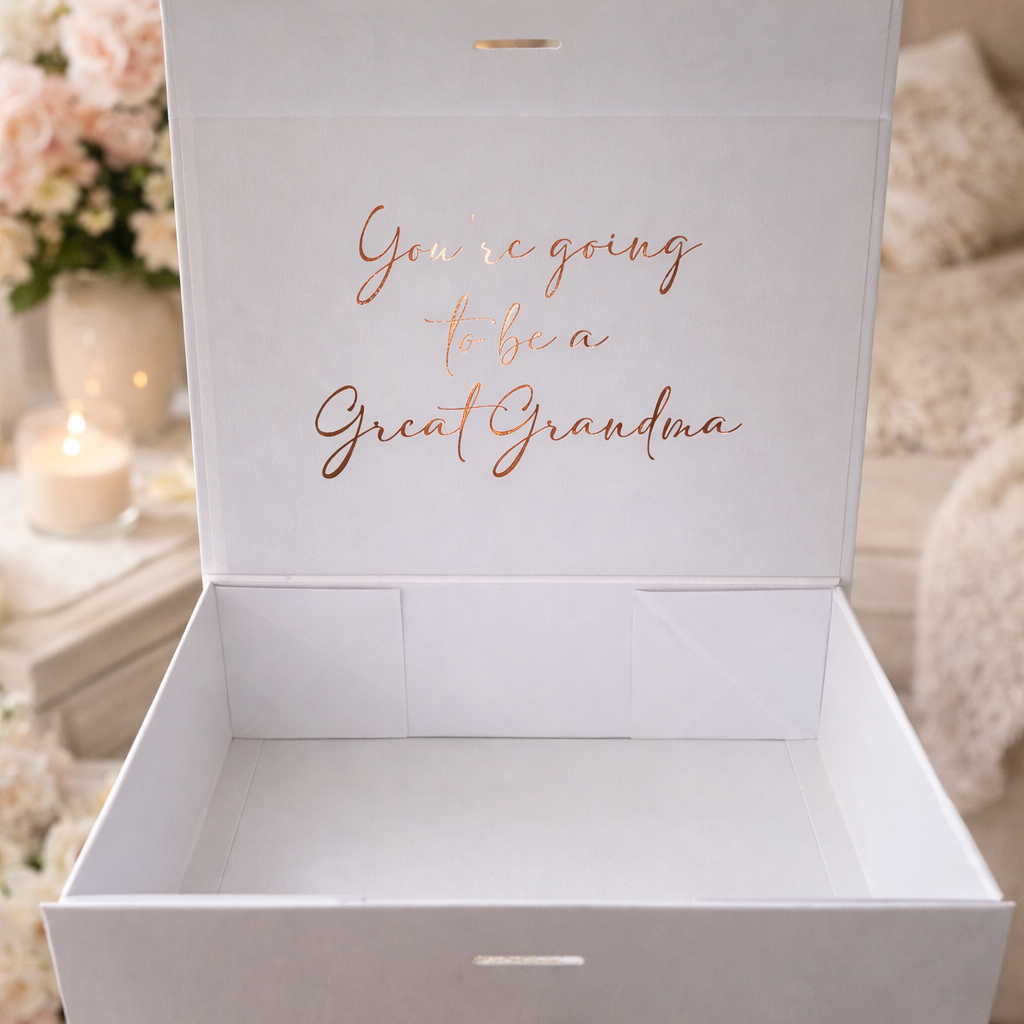 White gift box with 'You're going to be a Great Grandma' text, held by a hand.