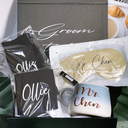 A gift box for the groom containing various personalized items including a black stubby holder, personalized socks, an eye mask, and a bottle opener, all packaged in a box with 'Groom to Mr. Chen' printed on it.