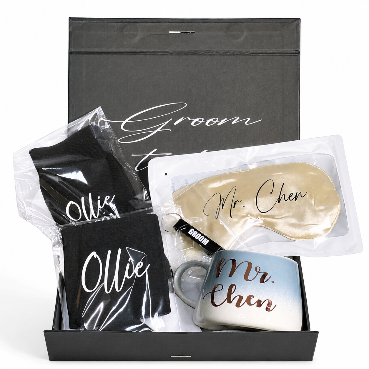 Gift set with mugs, sleep mask, and black pouches labeled 'Ollie' and 'Mr. Chen' in a black box.