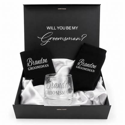Groomsman proposal box with glass, black shirt, and black card inside a black box.