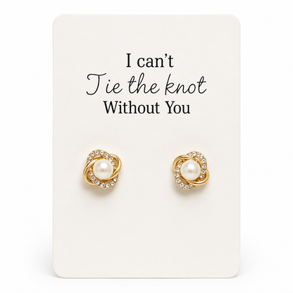 Gold earrings with pearls on a card that reads 'I can't tie the knot without you' on a white background