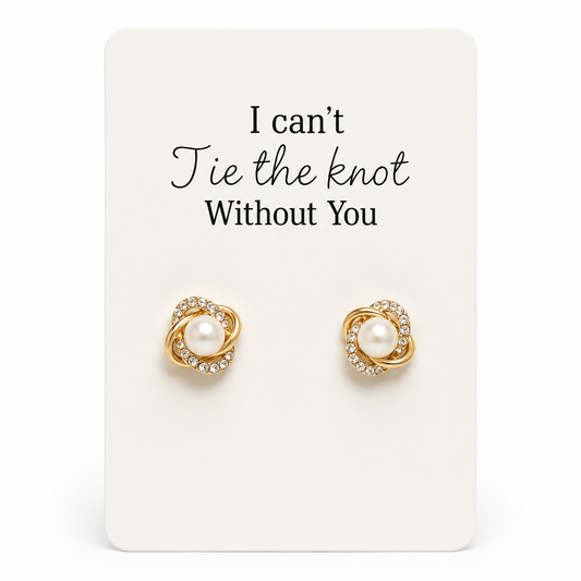 Gold earrings with pearls on a card that reads 'I can't tie the knot without you' on a white background