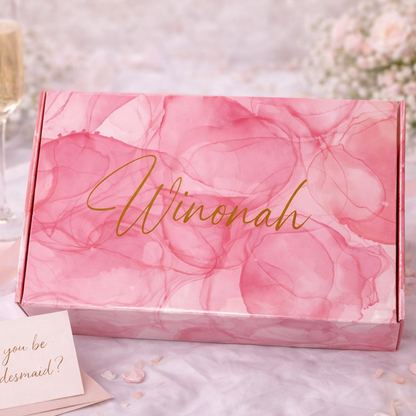 Pink floral box with 'Winonah' branding, champagne flute, card, and ring on a decorative background.