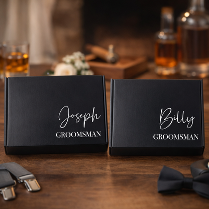 Two black groomsmen gift boxes labeled 'Joseph' and 'Billy' with a blurred background of a bar setting.