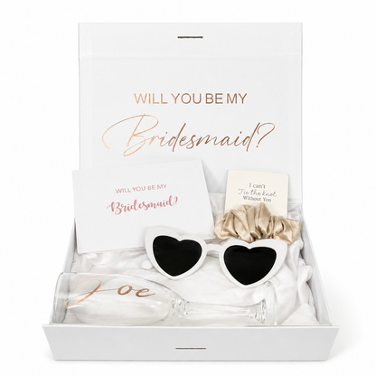 Gift set with heart-shaped sunglasses, bow, and card in a box asking 'Will you be my bridesmaid?'