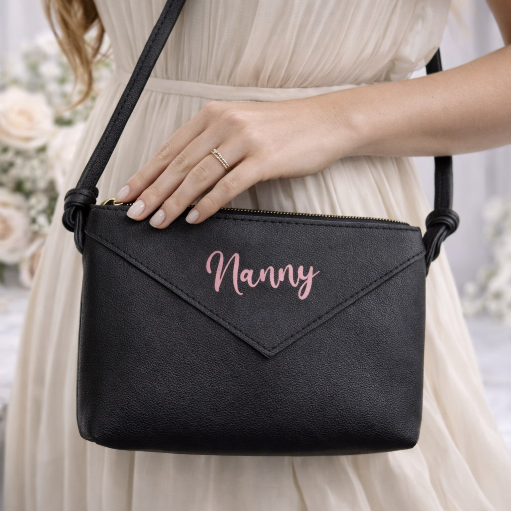 Black handbag with 'Nanny' text held by a person in a formal setting.