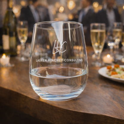 Clear glass with 'LHC Lauren Hincheny Consulting' branding on a wooden table with blurred background