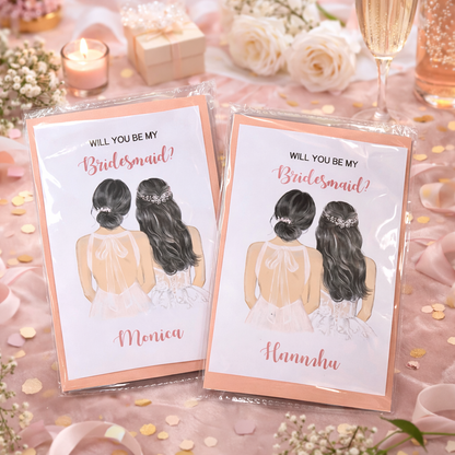 Two 'Will You Be My Bridesmaid?' cards on a decorative table with flowers and candles.