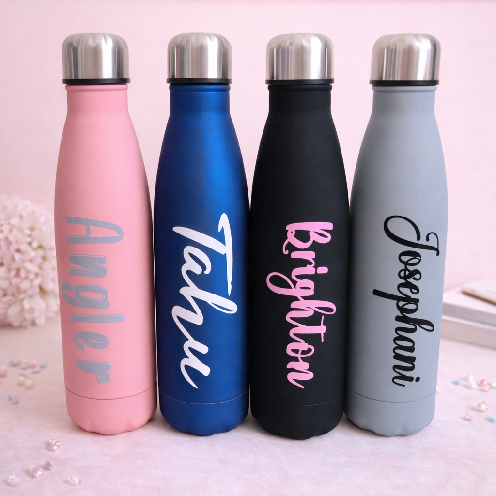 Four insulated water bottles in pink, blue, black, and gray with personalized names on a light pink background.