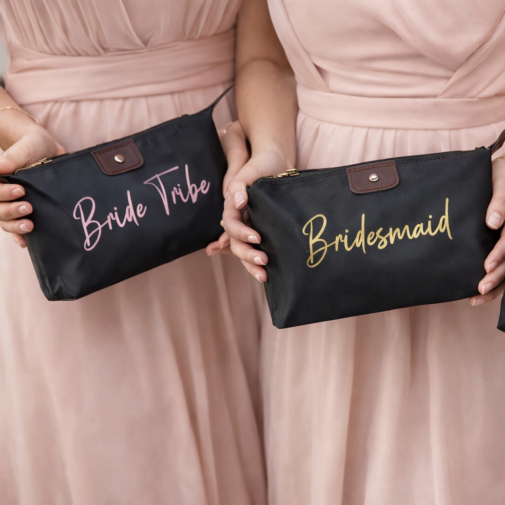 Three women in pink dresses holding black pouches labeled 'Bride Tribe', 'Bridesmaid', and 'Bride Squad'.