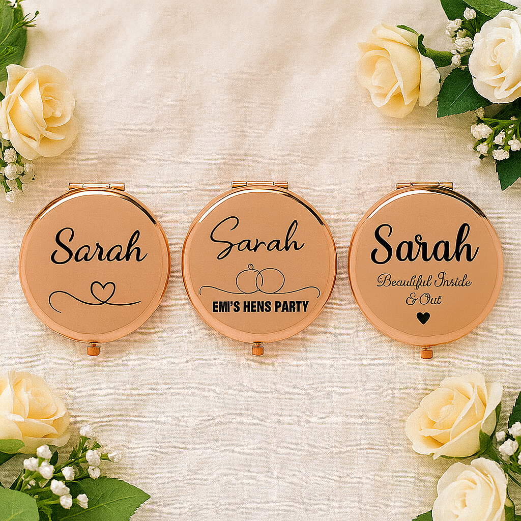 Three compact mirrors with 'Sarah' engraved, surrounded by white roses on a soft background.