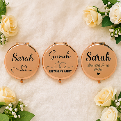 Three compact mirrors with 'Sarah' engraved, surrounded by white roses on a soft background.
