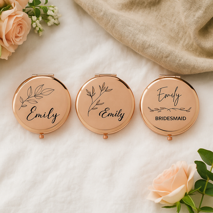 Three rose gold compact mirrors with 'Emily' and 'Bridesmaid' text on a light background with flowers.