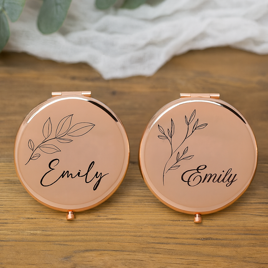 Two round compact mirrors with 'Emily' and leaf design on a wooden surface.