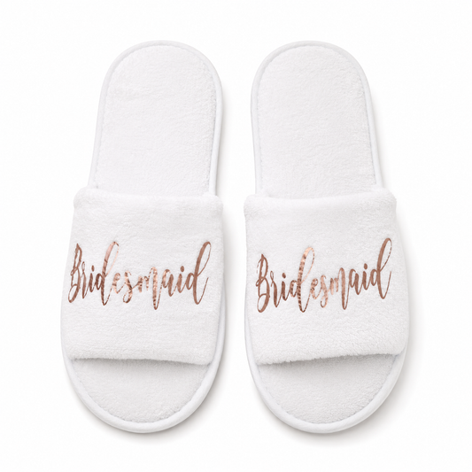 White slippers with 'Bridesmaid' text in rose gold on a white background