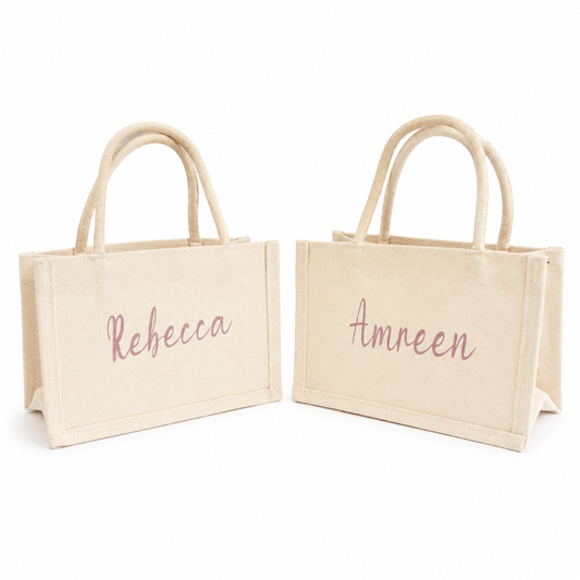 Two beige tote bags with 'Rebecca' and 'Amreen' embroidered on a white background