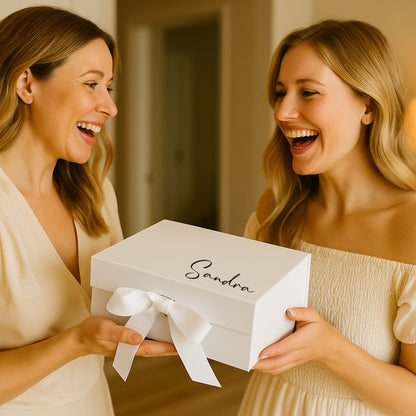 Two women laughing and holding a white box with 'Sandra' on it.