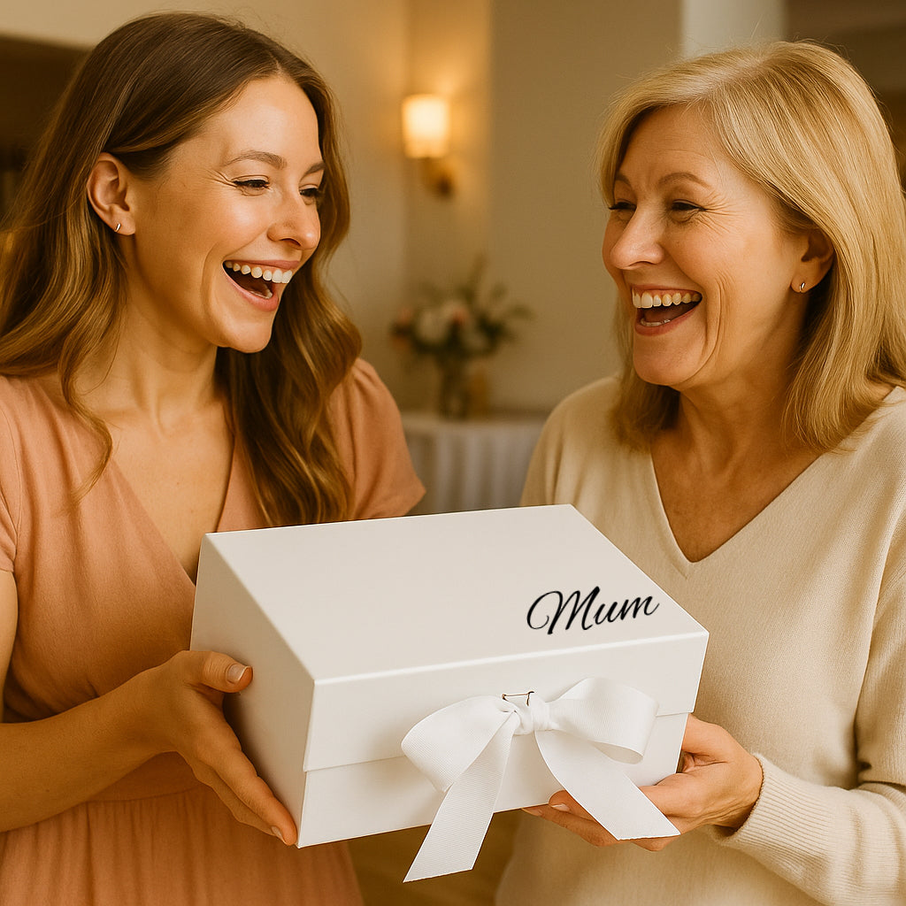 Two women laughing and holding a white box with 'Mum' on it.