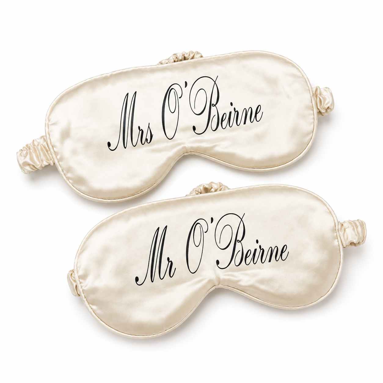 Two cream-colored satin eye masks with 'Mrs O'Beirne' and 'Mr O'Beirne' text on a white background.
