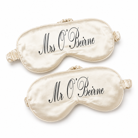 Two cream-colored satin eye masks with 'Mrs O'Beirne' and 'Mr O'Beirne' text on a white background.