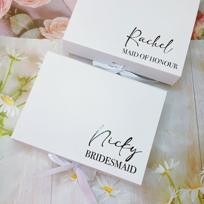 Two white ribbon magnetic gift boxes with custom text. One box is labeled 'Rachel' for a Maid of Honour and the other is labeled 'Nicly' for a Bridesmaid.