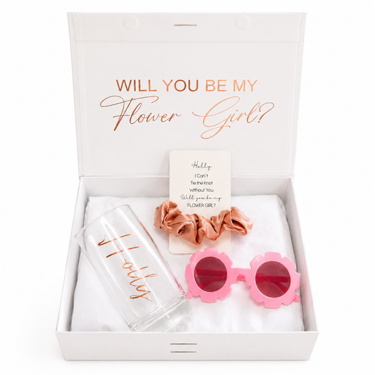 Gift set with 'Will You Be My Flower Girl?' message, including sunglasses, hair accessories, and a glass.