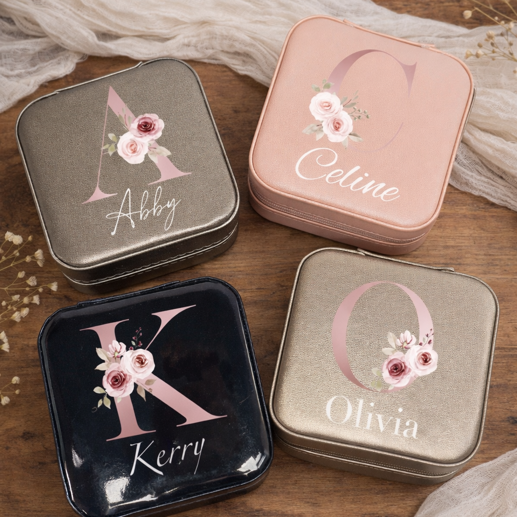 Four small tin boxes with personalized names and floral designs on a wooden surface.