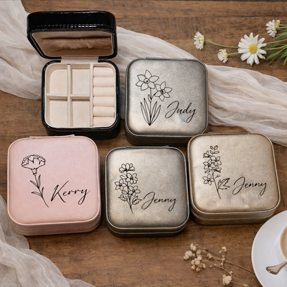 Set of small, decorative boxes with names engraved on them, placed on a wooden surface with flowers and a cup of tea.