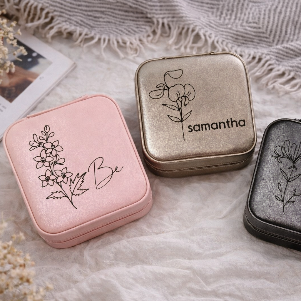 Three small jewelry boxes with floral designs and names on a textured fabric background
