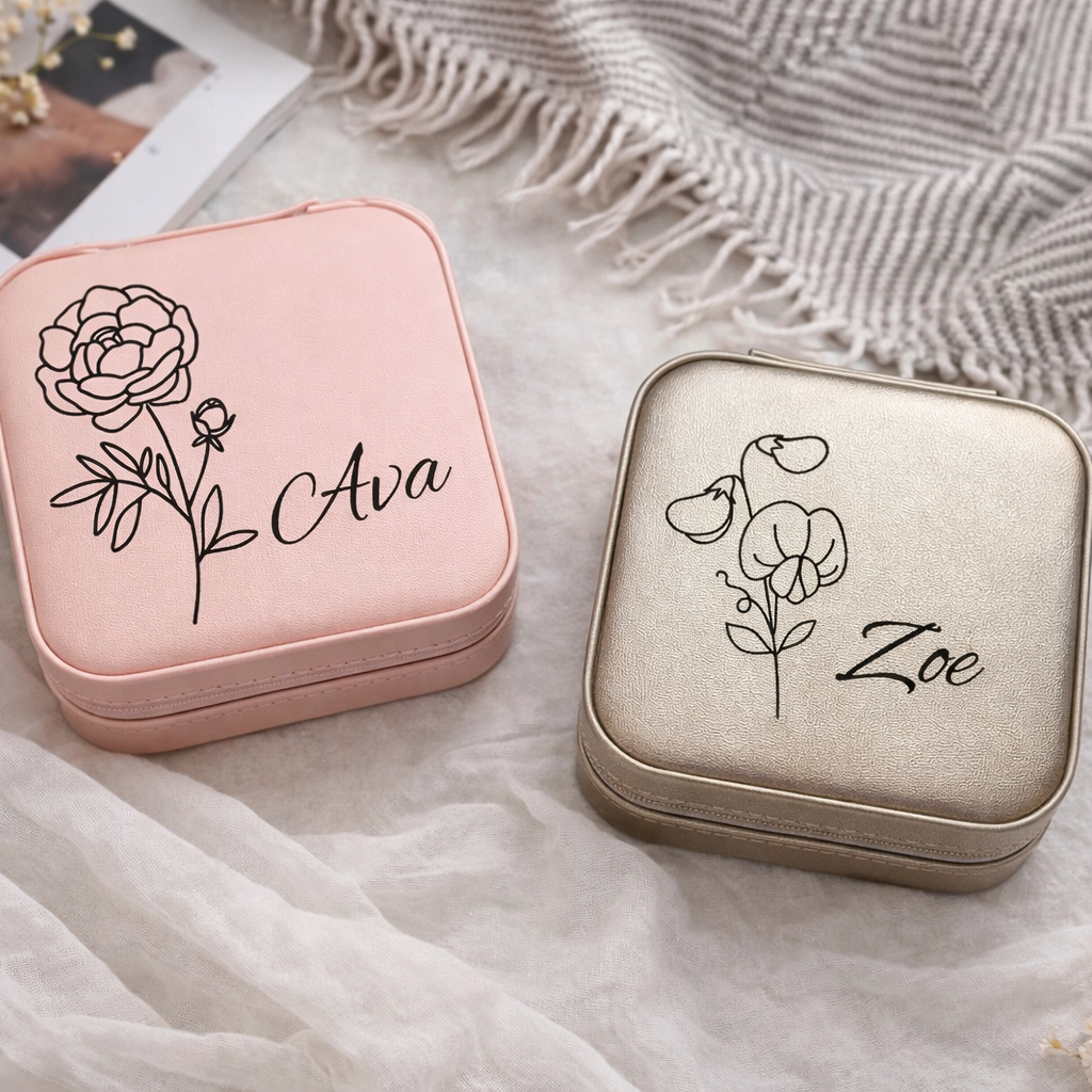 Two small jewelry boxes, one pink and one beige, with engraved names 'Ava' and 'Zoe' on a textured surface.