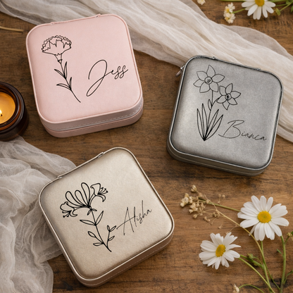 Three small tin boxes with floral designs and names on a wooden surface with daisies.