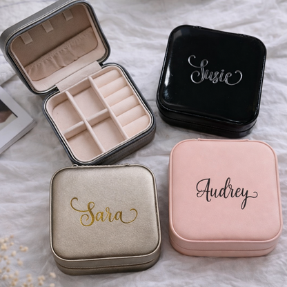 Four jewelry boxes with names 'Sara', 'Audrey', 'Susie', and a gold coin on a textured surface.