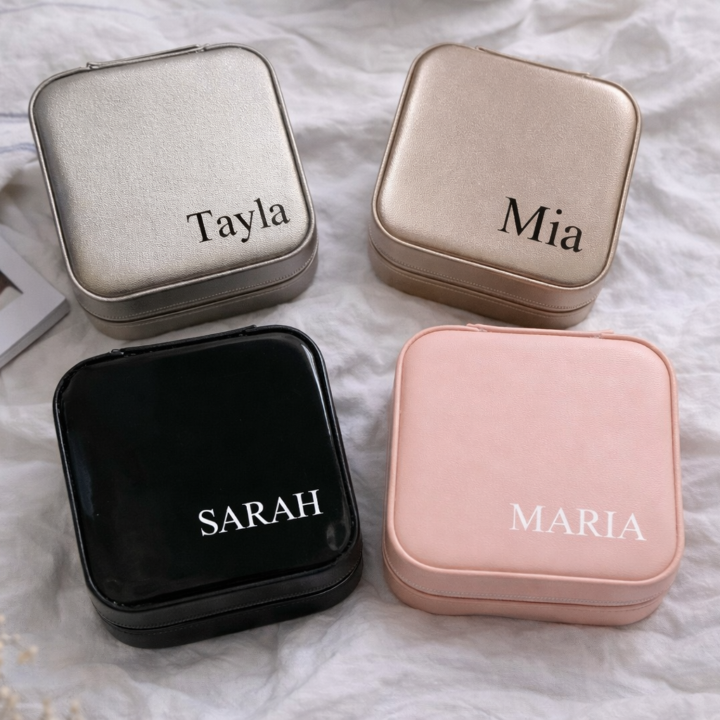 Four square jewelry boxes with names 'Tayla', 'Mia', 'Sarah', and 'Maria' engraved on them, placed on a textured surface.
