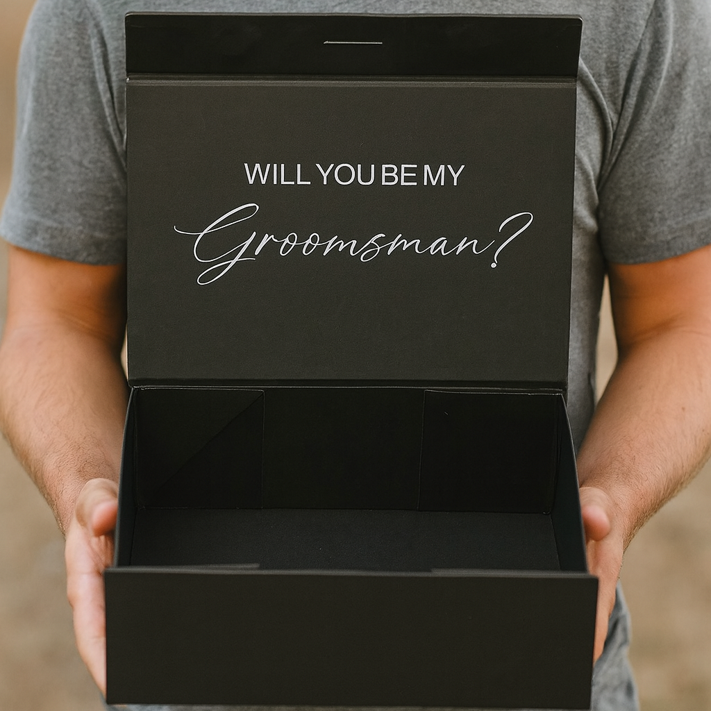 Man holding a black box with 'Will You Be My Groomsman?' text.
